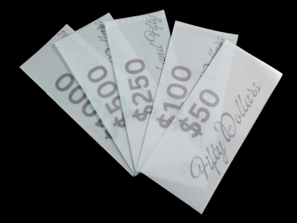 Five white envelopes with dollar amount markings on a wooden surface